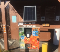 A colorful machine titled "Pay Station" stands in front of a wooden kiosk. 