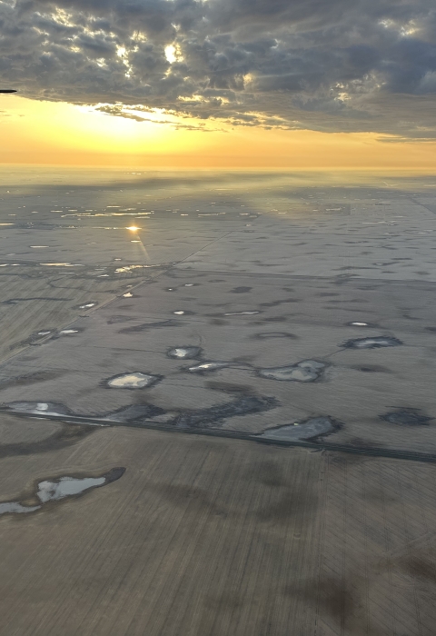 view of an airplane wing over a landscape of wetlands