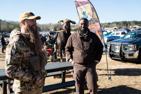 A man in a brown uniform stands in front of a FWS banner