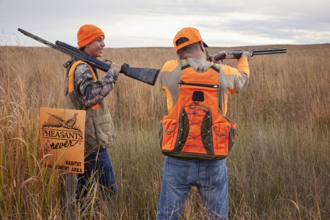 Father and son in hunter blaze orange vests.