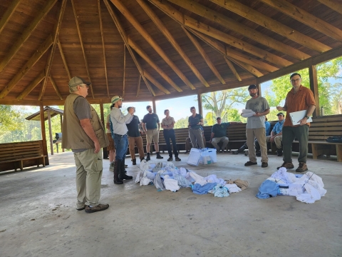 a group of people standing under a pavilion surrounding a pile of pillowcases on the ground