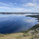 scenic landscape with forest and water with a light blue sky above