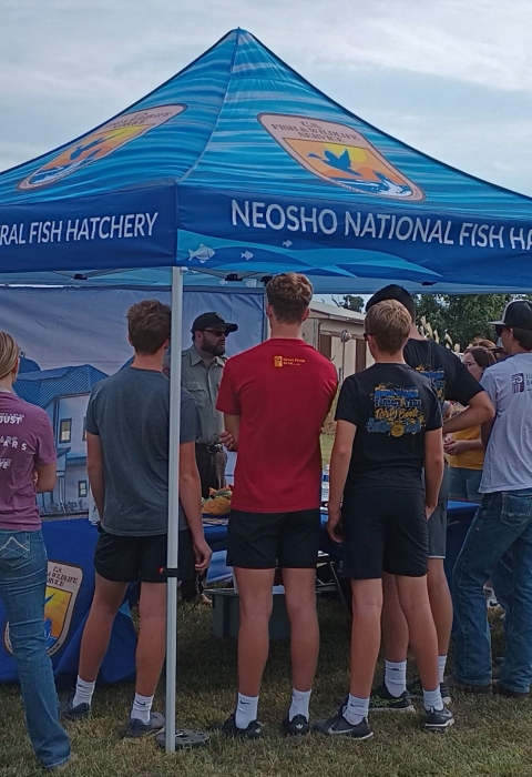 high school students gather under a display tent at an outdoor career fair