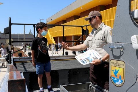 A man and a boy talk aboard a boat on land