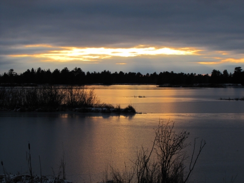 Sunset over frozen pond with heavy clouds
