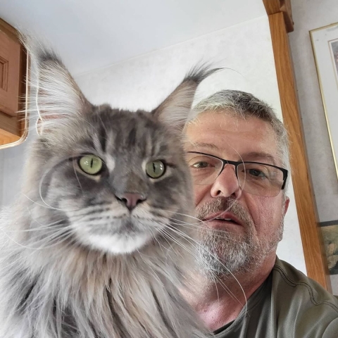 Man and gray cat take picture together.