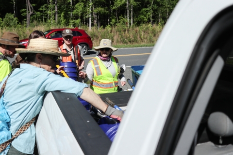 Several people around the bed of a pick-up truck, picking up tools from the bed