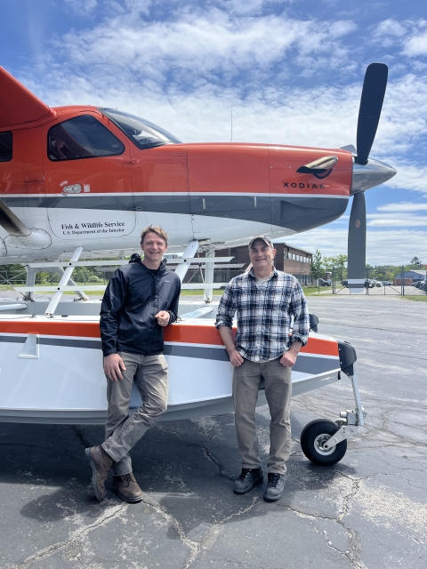 two pilot biologists standing by a plane