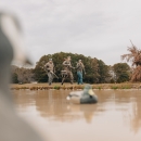 Three hunters in camouflage walk past duck decoys.