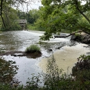 A view of a dam and river surrounded by trees.
