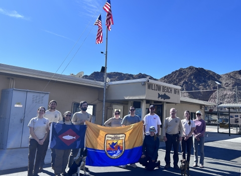 People in front of building holding USFWS flag and fish pennant, US flags fly from building 