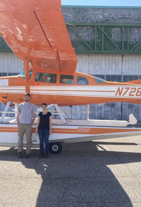 2 people stand in front of a survey aircraft