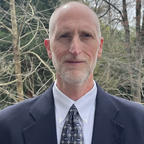 Close up of Mike Oetker in a suit with woods in the background.