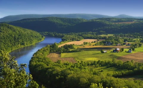 a river winds through lush farm land and rolling hills