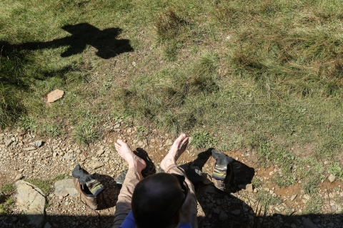 Man sitting down, resting bare feet on the ground
