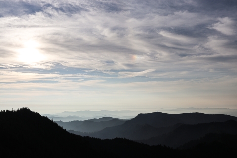Rolling, forest-covered mountains beneath a partly cloudy sky