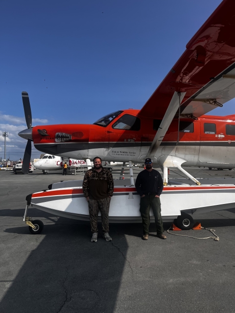 two pilot biologist standing by a plane