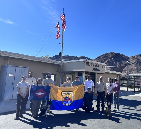 People in front of building holding USFWS flag and fish pennant, US flags fly from building 