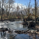 An excavator removing remnants of a dam from a river