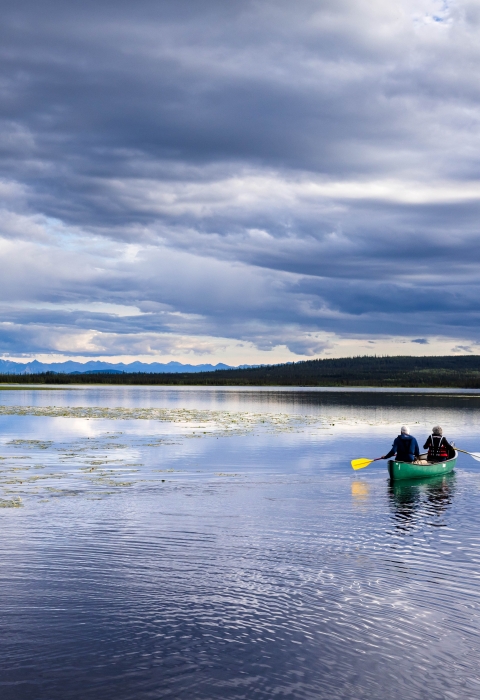 two people paddle a canoe on a large lake