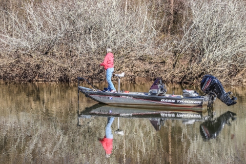 A person fishing from a motorized boat.