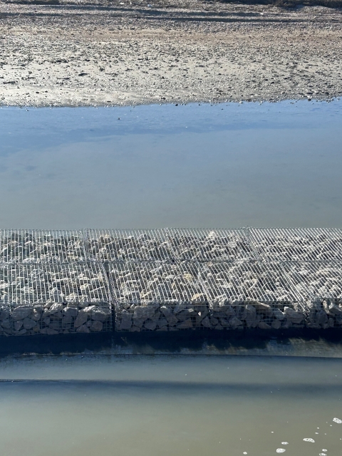 metal cage in water runs just off a coastline 