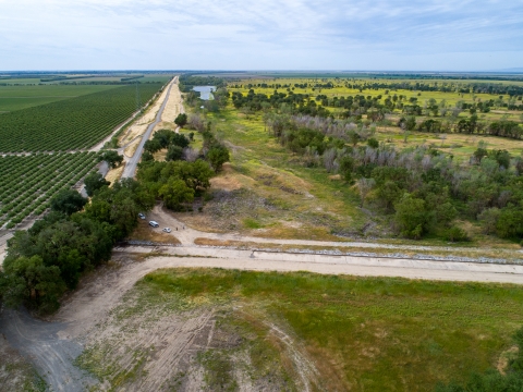 Large wildlife area with a road and rows of crops on the left side