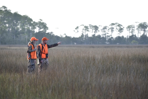 Two hunters in orange hunter outfit standing in the field.
