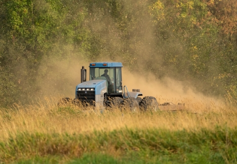 Tractor plowing through grass field.