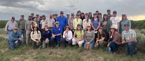 a group of 36 people pose for a picture outdoors with a cloudy sky