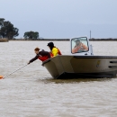 A woman leans out of a boat to pull in a net