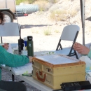 Two people sitting at a table preparing to band birds
