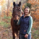 Bri Benvenuti, refuge biological technician at Rachel Carson National Wildlife Refuge, poses with her horse Marshall in fall with colorful leaves framing the two.