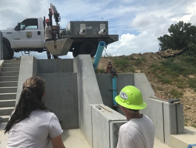 Edenton NFH staff lower bucket with a crane into dry kettle as a test before adding fish to pond.