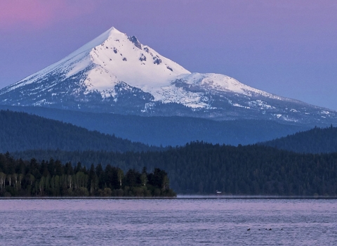 a body of water with a snow covered mountain in the background