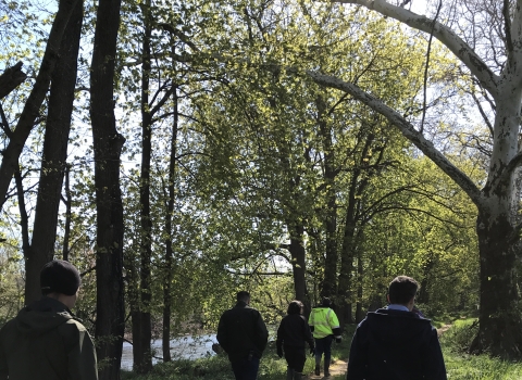 Group of people walking along stream.