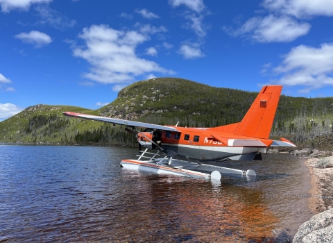 airplane floating on water with mountains in the background