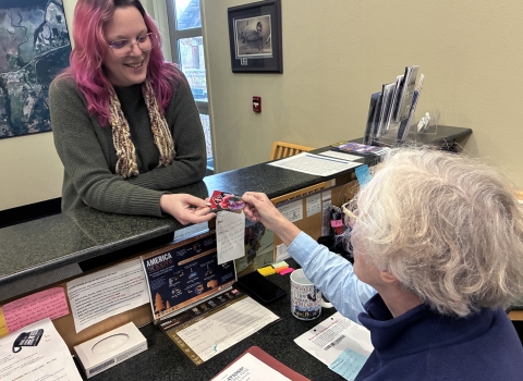 A volunteer hands a pass to a visitor